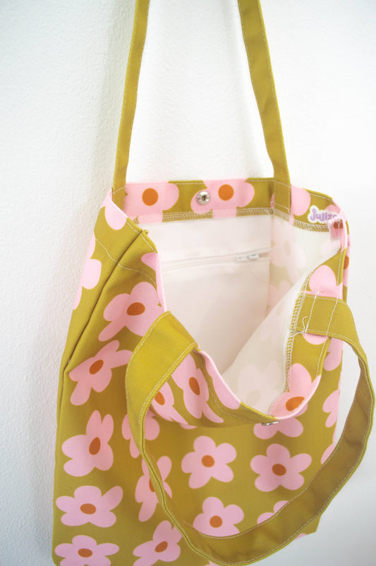 Tote bag Olive & Pink Flowers, de tela canvas con un diseño vibrante de flores en tonos oliva y rosa, incluye bolsillo interior con zipper y botón, ideal para uso diario y actividades al aire libre, ilustración exclusiva de Julizco