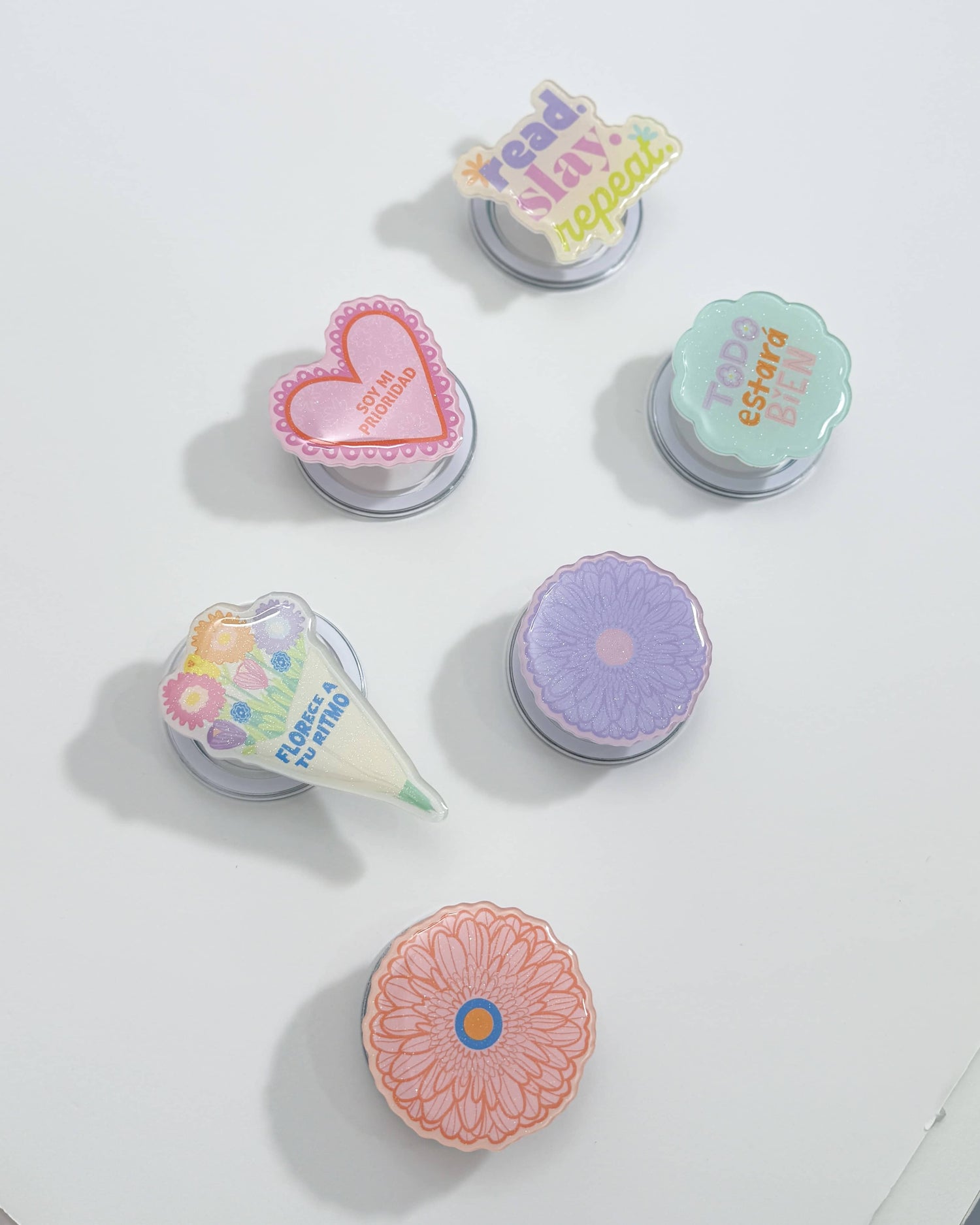 Tres Magnetic Grip Holders de acrílico brillante en diferentes colores, cada uno con un diseño atractivo, mostrando su tamaño compacto y estilo moderno.