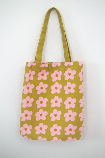 Tote bag Olive & Pink Flowers, de tela canvas con un diseño vibrante de flores en tonos oliva y rosa, incluye bolsillo interior con zipper y botón, ideal para uso diario y actividades al aire libre, ilustración exclusiva de Julizco