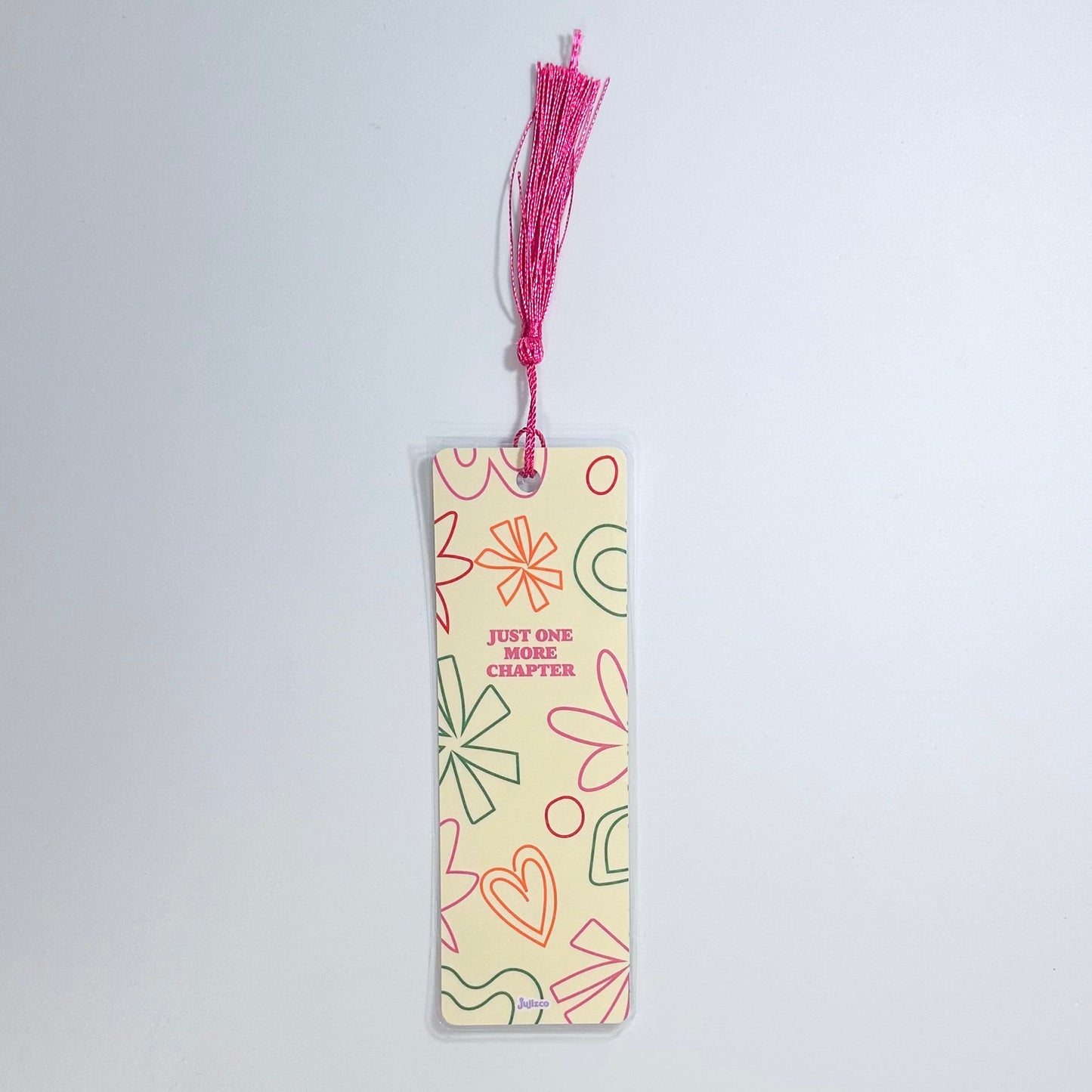 Bookmark en diseño que dice "Just One More Chapter" con tassel de color